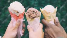 Three hands holding ice cream cones